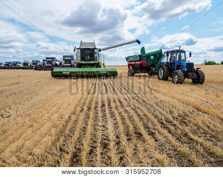 VILLAGE DECABRIST, SARTOV REGION, RUSSIA - AUGUST 03, 2019: Combine harvesters and tractors in the field for harvesting wheat