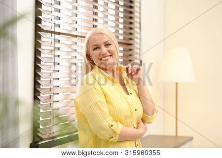 Portrait Of Happy Mature Woman Near Window Indoors