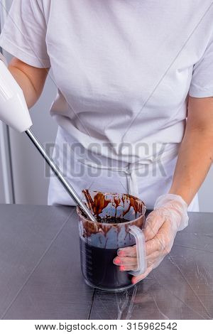 The Pastry Chef In The Kitchen Glazes Pastries. Cook Makes Chocolate Frosting With A Mixer. Master C