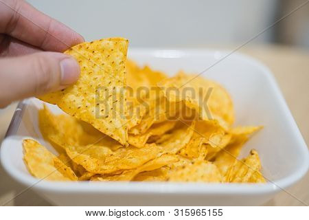 Man Hand Picking Up Corn Chip From White Bowl