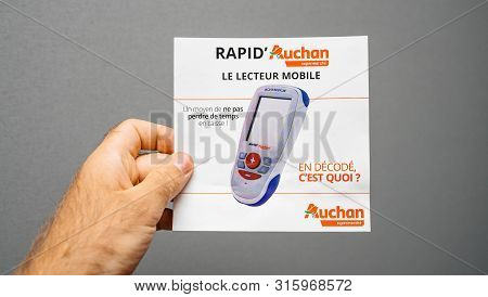 Paris, France - Sep 8, 2018: Man Hand Holding A Rapid Auchan Le Lecteur Mobile Mobile Reader Of Prod