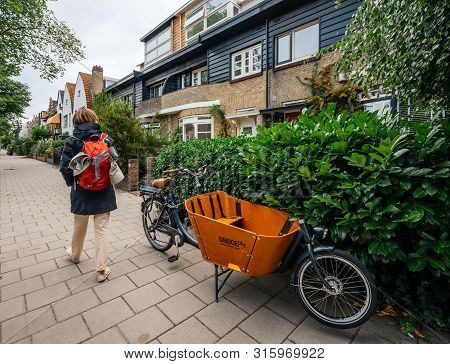 Haarlem, Netherlands - Aug 16, 2018: Rear View Of Woman With Backpack Walking On Tiny Street With Pa