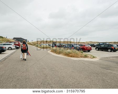Overveen, Netherlands - Aug 16, 2018: Rear View Of Single Woman Walking To The Car Parking Of A Dutc