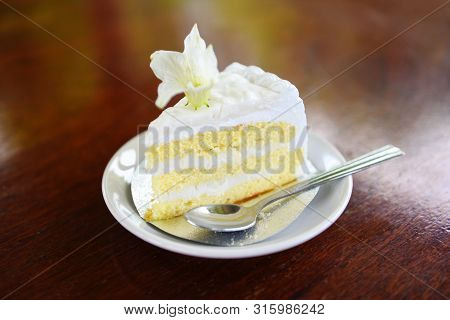 Cake Slice On White Palte With Flower On Wooden Table Background / Delicious Coconut Cake And Spoon