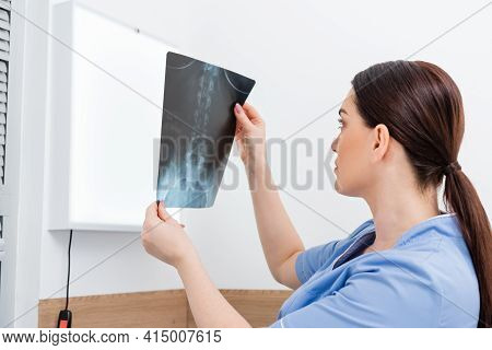 Brunette Rehabilitologist Looking At X-ray In Hospital.