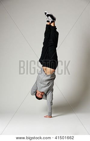 voller Länge Portrait von cool b-Boy auf der einen Seite gegenüber dem grauen Hintergrund