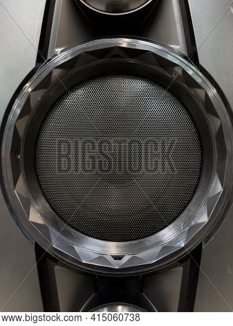 Close-up of musical stereo speaker with protective grill. Modern black audio speaker or music column for background.