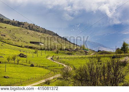 Rural Landscape. Road, Emerald Hills, Tractor. Farm Fields In The Mountains. Village In North Osseti