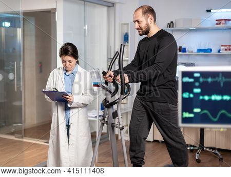 Sport Researcher In Laboratory Taking Notes While Muscular Athlete Athlete Is Running