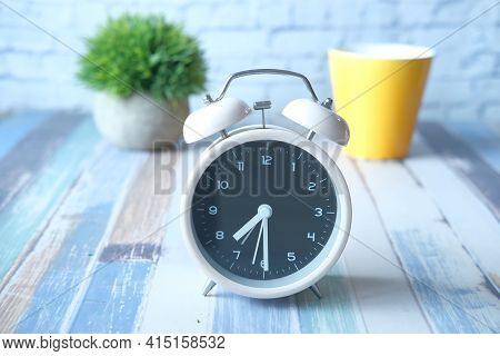 Old Alarm Clock And Yellow Color Coffee Mug On Table