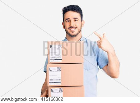 Young hispanic man holding delivery package pointing finger to one self smiling happy and proud 
