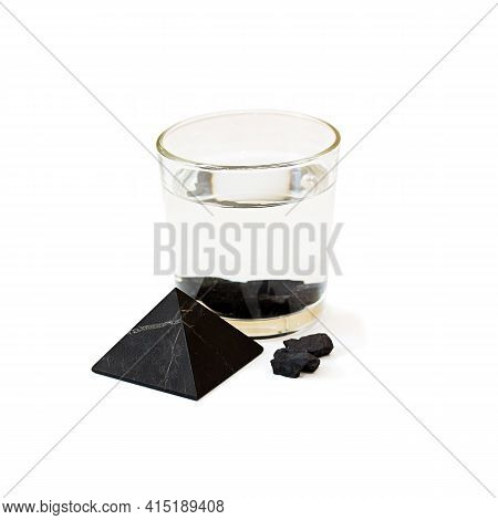 Water With Shungite In A Glass On A White Background. Shungite Pyramid. Water Purification With Shun