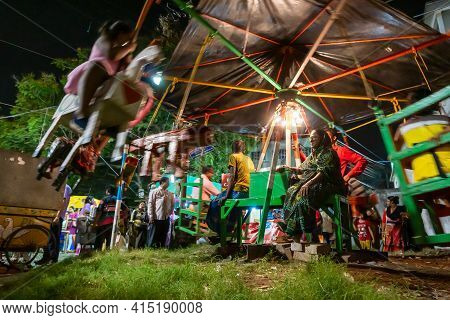 Howrah, West Bengal, India -14th April 2019: Aged Woman Watching Over Children Riding On Nagordola- 