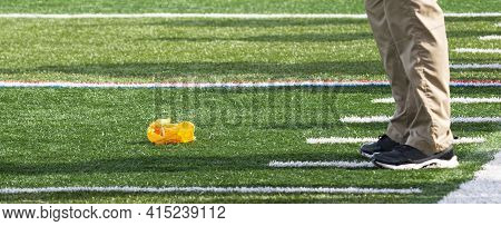Football Official Throws The Yellow Flag On The Ground In Front Of The Heach Coaches Feet.