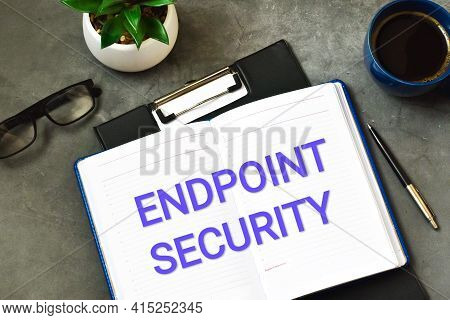 Endpoint Security Text Written In A Notebook Next To A Green Plant, Calculator, Glasses And A Cup Of