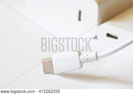 A White Usb Type-c Connector With A Wire Lies Against A Light Background Next To Two Matching White 