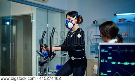 Woman Athlete With Mask Running On Cross Trainer