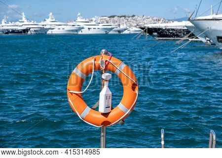 Lifebuoy Orange On Vertical Iron, Sea, Boats, Town Background.