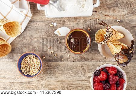 Top View Image Of A Table Where Hand Rolled Fresh Made Waffle Cones Are Dipped Into Melted Chocolate