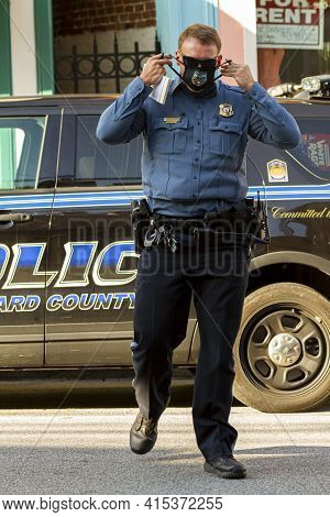 Ellicott City, Md, Usa 10/07/2020: A Young Caucasian Male Police Officer Is Crossing The Street. He 