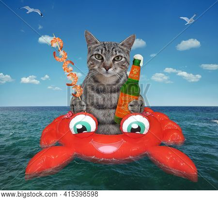 A Gray Cat Drinks Beer And Eats Shrimp On An Inflatable Crab In The Open Sea.