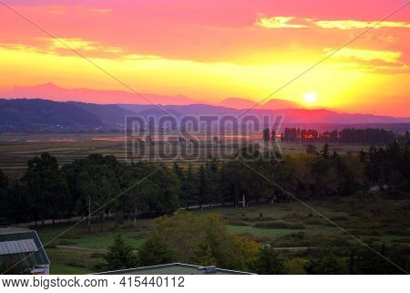 The Sun Sets Behind The Mountains In The Tropics. Sunset In Pitsunda. Mountains And Plains With Euca