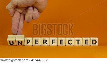Perfected Or Unperfected Symbol. Businessman Turns Wooden Cubes And Changes The Word Unperfected To 