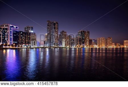 Sharjah,UAE - Dec 2nd 2020. Panoramic view of the illuminated sky scrappers  showing beautiful reflections in water captured at the Al Majaz waterfront Sharjah , UAE.