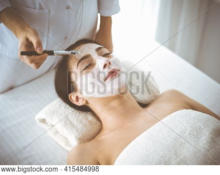 Beautiful Brunette Woman Enjoying Applying Cosmetic Mask With Closed Eyes Comfortable And Blissful. 