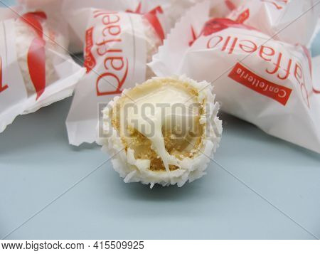 Rafaello Candies In A Wrapper On A Blue Background. One Candy Is Cut And The Cream Filling Is Visibl