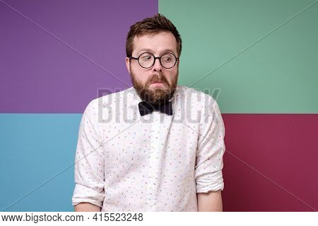 Bizarre Man In Round Glasses, A Shirt And A Bow Tie Hunched Shoulders In Bewilderment And Looks Down