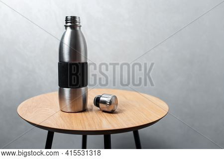 Close-up Of Steel Reusable Thermo Water Bottle And Tin On Wooden Table Against Background Of Texture