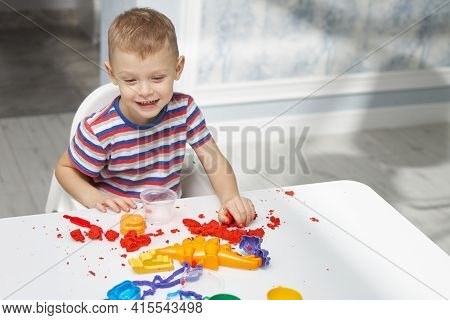 A Cheerful Little Boy In A Bright T-shirt Plays With Kinetic Sand. Educational Childrens Game With B