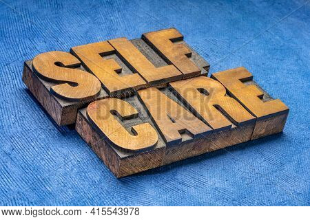 self care word abstract in vintage letterpress wood type against blue  handmade paper - mental, emotional, and physical health concept