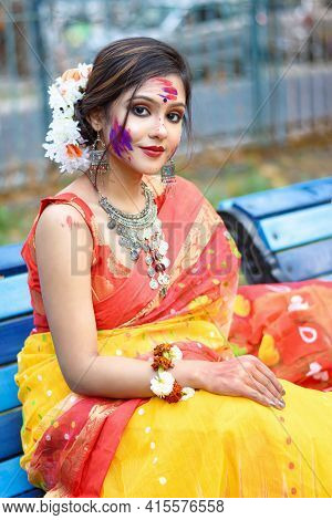 Portrait Of Pretty Young Indian Girl Wearing Traditional Saree And Jewellery, Sitting On A Bench On 