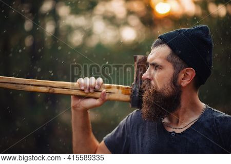 A Serious Man With A Thick Beard And A Large Mustache In A Dark Sleeveless T-shirt And A Warm Hat Wi