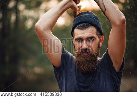 A Wet Bearded Man With A Thick Beard And A Large Mustache In A Dark Sleeveless T-shirt And A Warm Ha
