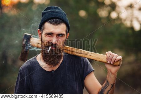 Adult Brutal Bearded Man Lumberjack With A Long Beard And Mustache In A T-shirt And A Warm Hat With