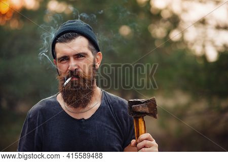 Stylish Brutal Bearded Man Lumberjack With A Long Beard And Mustache In A T-shirt And A Warm Hat Wit