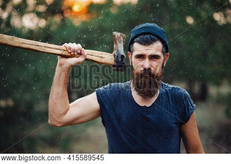 Lumberjack Man With A Thick Beard And A Large Mustache In A Dark Sleeveless T-shirt And A Warm Hat W