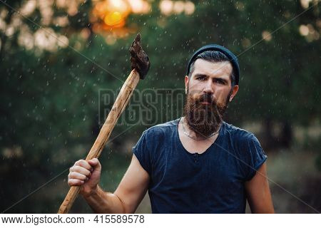 Man With A Thick Beard And A Large Mustache In A Dark Sleeveless T-shirt And A Warm Hat With Gray Ha