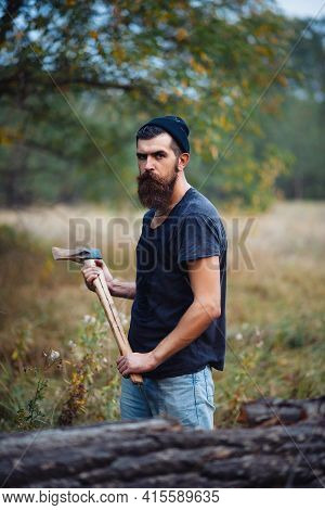 Serious Man With A Thick Beard And A Large Mustache In A Dark Sleeveless T-shirt And A Warm Hat With