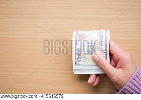 Hand Holding 100 Dollas Bank Note With Sweater On Wooden Table For Pay In Shopping. Planing Earn Mon
