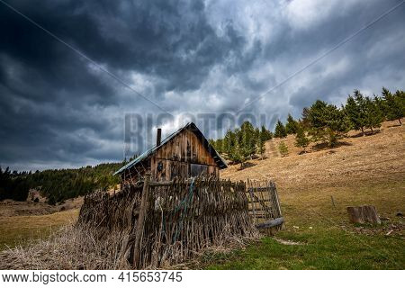 Gathering Stormclouds Over A Small Wooden Cabin At Spring Time In Transylvania, Romania.