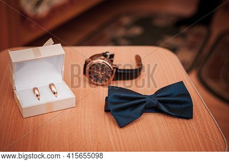 Tiebow Gold Rings And Wristwatch On The Table