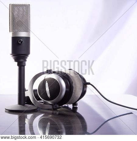 Professional Condenser Microphone And Headset On Reflective Surface And Light Background, Selective
