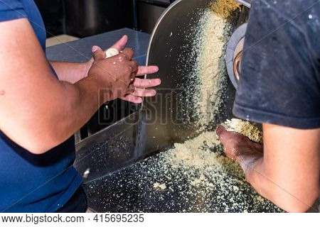 Arms Of Two Men Holding Fresh Dough In The Mill