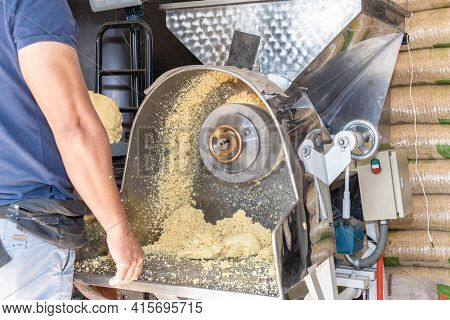 Front View Of A Nixtamal Mill While A Man Takes Out The Dough That Is Being Produced