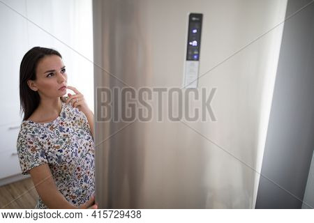 Pretty, young woman in her modern kitchen, by the fridge, about to cook a healthy meel for her family (color toned image)