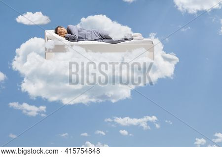 Man sleeping peacefully up in the clouds floating on his bed